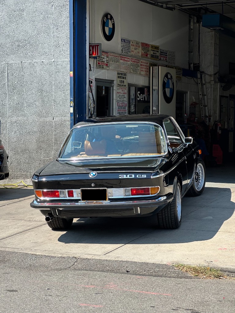 Black BMW 3.0 CS coupe parked outside a BMW service garage